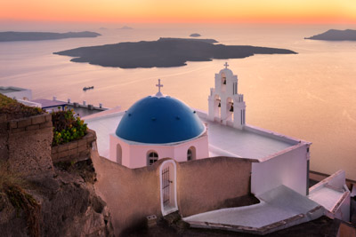Saint Theodore Church in Fira at sunset, with its blue dome and white bell tower above the caldera and the Aegean Sea, Santorini, Greece