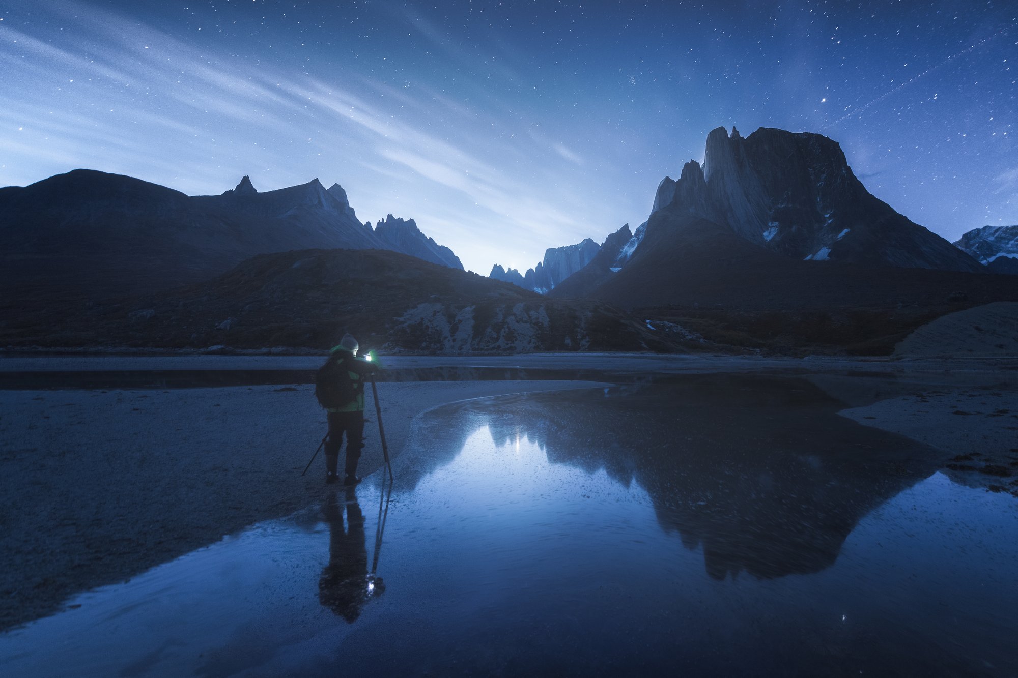 Andrei Omelianchuk with a camera on a tripod by a mountain lake in South Greenland at dusk
